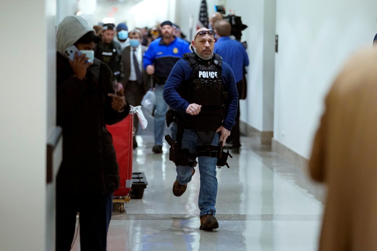 People run in the halls as protesters try to break into the House Chamber at the U.S. Capitol on Wednesday, Jan. 6, 2021, in Washington.