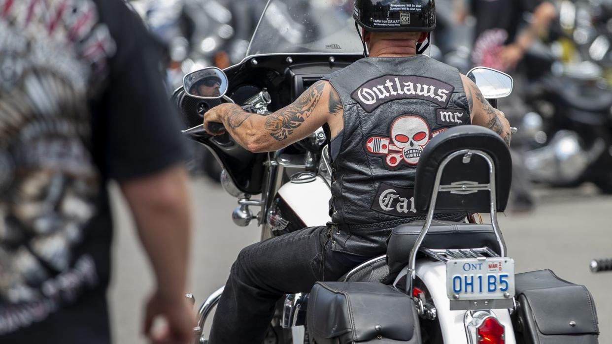 a motorcycle rider wearing a leather jacket with a skull and pistons logo