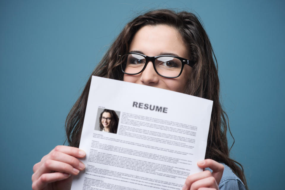 Smiling woman holding up her resume.
