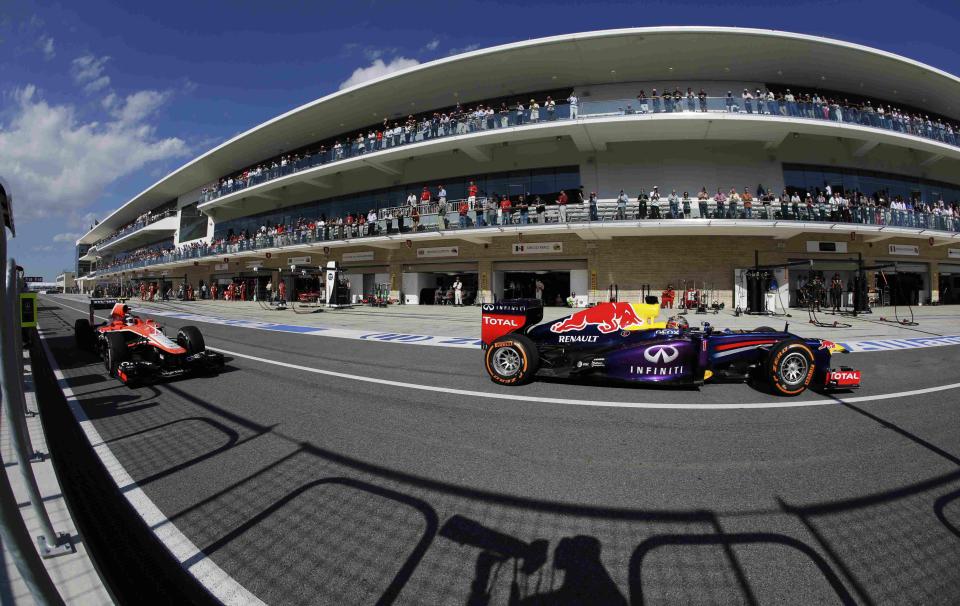 Marussia Formula One driver Max Chilton (L) of Britain drives next to Red Bull Formula One driver Sebastian Vettel of Germany in the pits during the Austin F1 Grand Prix at the Circuit of the Americas in Austin November 17, 2013.