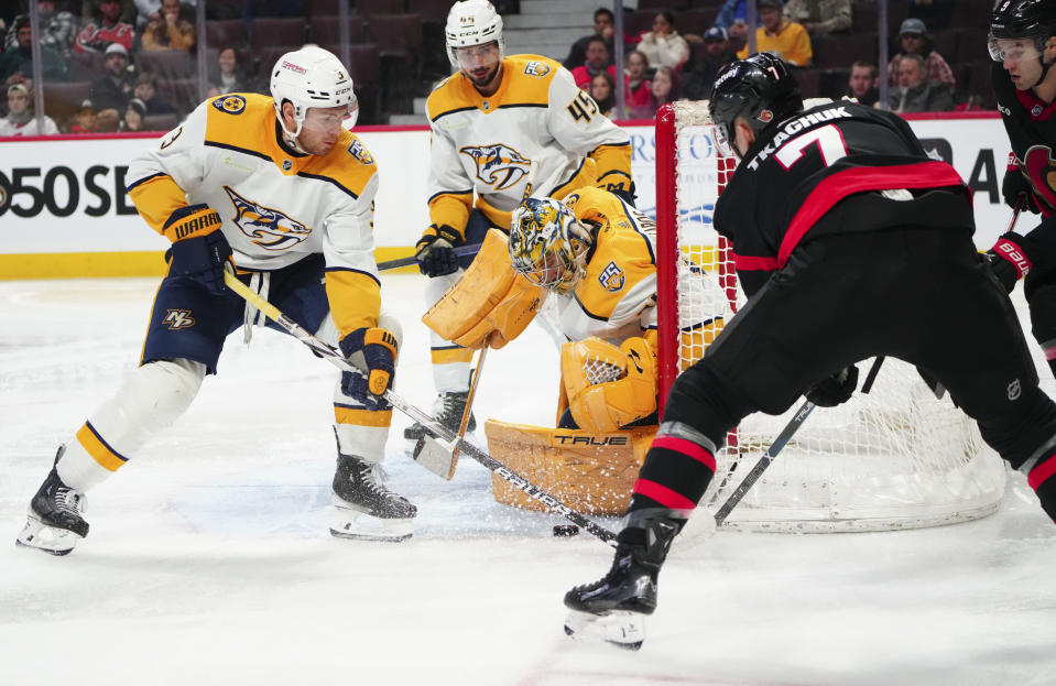 Nashville Predators goaltender Juuse Saros (74) keeps his eye on the puck along with teammate defenseman Jeremy Lauzon (3) as Ottawa Senators left wing Brady Tkachuk (7) attempts to wrap the net during the second period of an NHL hockey game in Ottawa, Ontario, Monday, Jan. 29, 2024. (Sean Kilpatrick/The Canadian Press via AP)