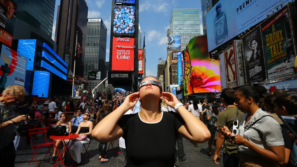  A woman observes the total solar eclipse with solar eclipse glasses at the Times Square in New York City, United States on August 21, 2017. . 