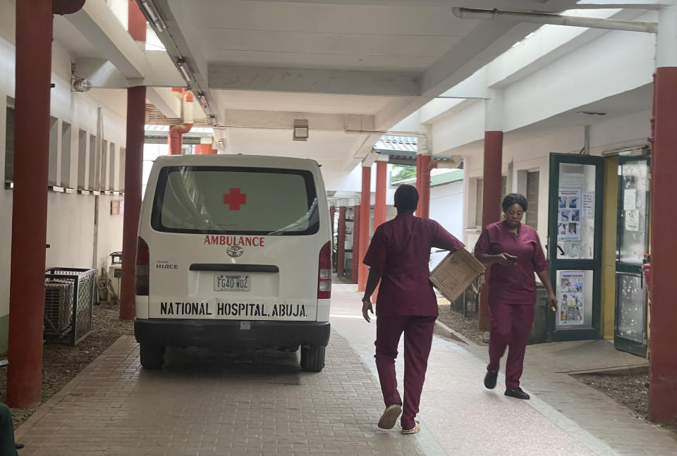 Workers walk past an ambulance parked outside a ward of the national hospital in Abuja Nigeria, Wednesday, July 26, 2023. The Nigerian Association of Resident Doctors on Wednesday is on strike again, demanding better working conditions for its members. (AP Photo/Chinedu Asadu)