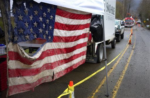 An American flag pulled from the debris hangs in the staging area at the west side of the mudslide on Highway 530 near mile marker 37, in Arlington, Wash., on Sunday, March 30, 2014. Periods of rain and wind have hampered efforts the past two days, with some rain showers continuing today. Last night, the confirmed fatalities list was updated to 18, with the number of those missing falling from 90 to 30. (AP Photo/Rick Wilking, Pool)