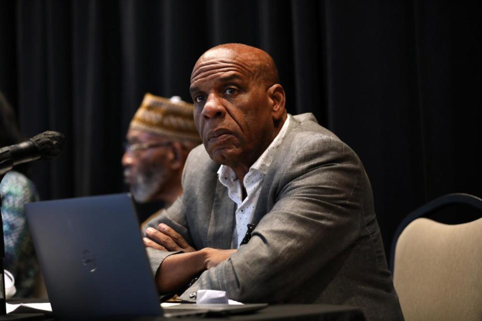 A man wearing a gray jacket sits at a table.