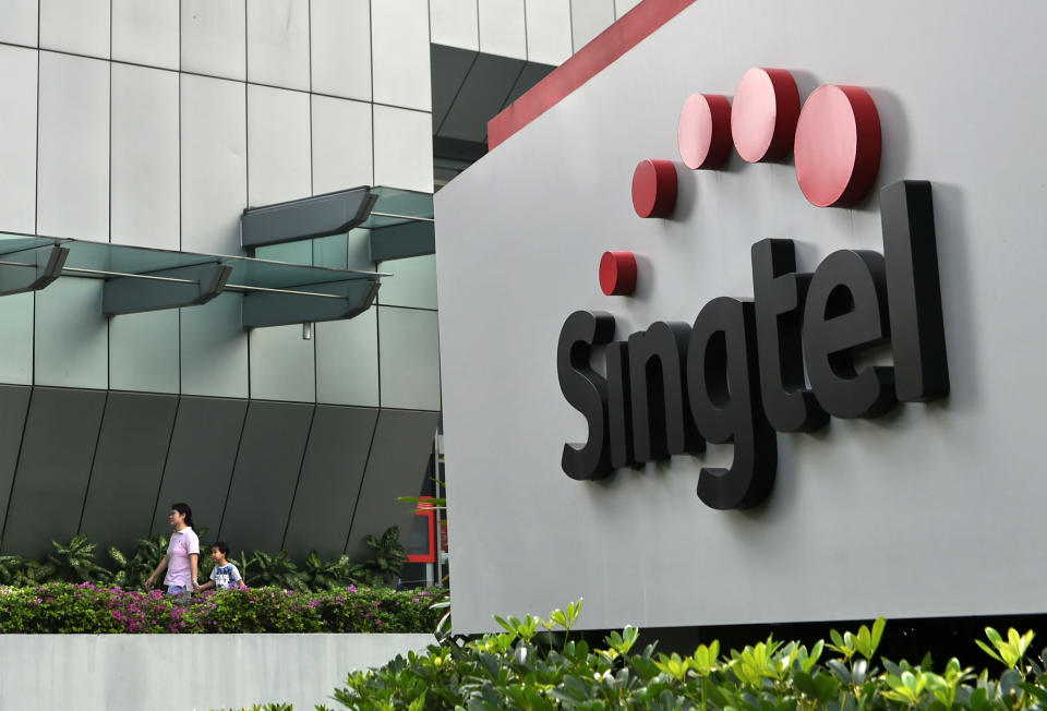 A woman and a child walk out of the Singapore Telecommunications (Singtel) building in Singapore on February 12, 2016.  Singtel reported a 1.7 per cent fall in third-quarter net profit of 683 million US dollar for the three months ended December, compared with 694 million US dollar a year ago, as adverse currency movements and investments offset growing mobile data usage by its customers.  AFP PHOTO / ROSLAN RAHMAN (Photo by Roslan RAHMAN / AFP) (Photo by ROSLAN RAHMAN/AFP via Getty Images)