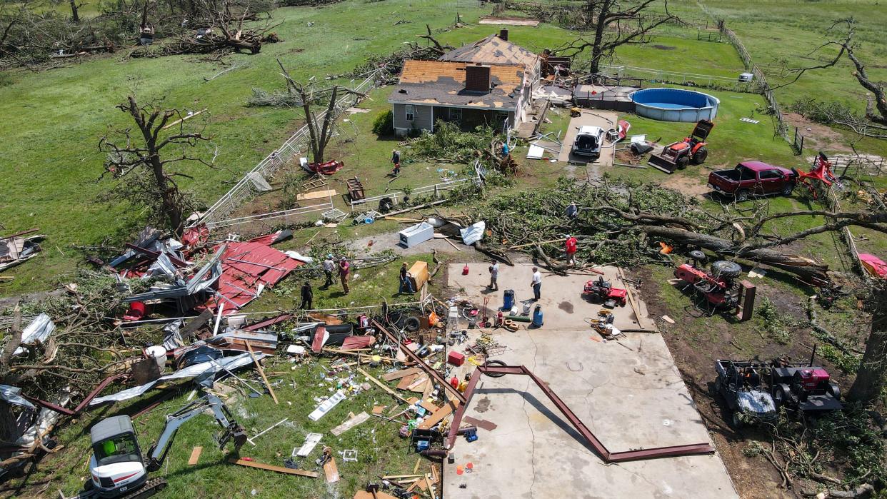 People help clean up storm damage at a family's home Sunday in Pryor. Two women were killed during the storm at a home next door.