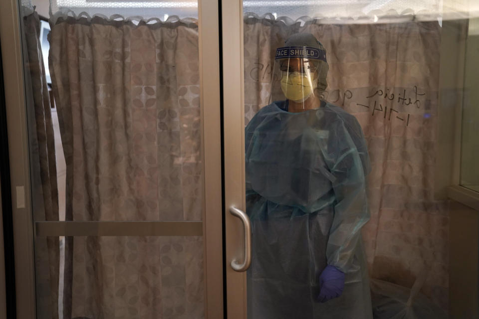 Registered nurse Merri Lynn Anderson talks to her patient with a curtain drawn between them to give the patient privacy in a COVID-19 unit at St. Joseph Hospital in Orange, Calif., Thursday, Jan. 7, 2021. California health authorities reported Thursday a record two-day total of 1,042 coronavirus deaths as many hospitals strain under unprecedented caseloads. The state's hospitals are trying to prepare for the possibility that they may have to ration care for lack of staff and beds — and hoping they don't have to make that choice. (AP Photo/Jae C. Hong)