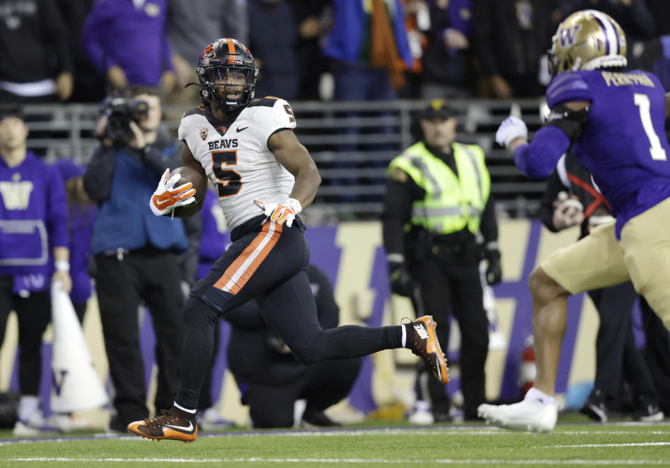 Oregon State running back Deshaun Fenwick (5) runs for a touchdown as Washington cornerback Jordan Perryman (1) pursues during the second half of an NCAA college football game Friday, Nov. 4, 2022, in Seattle. (AP Photo/John Froschauer)