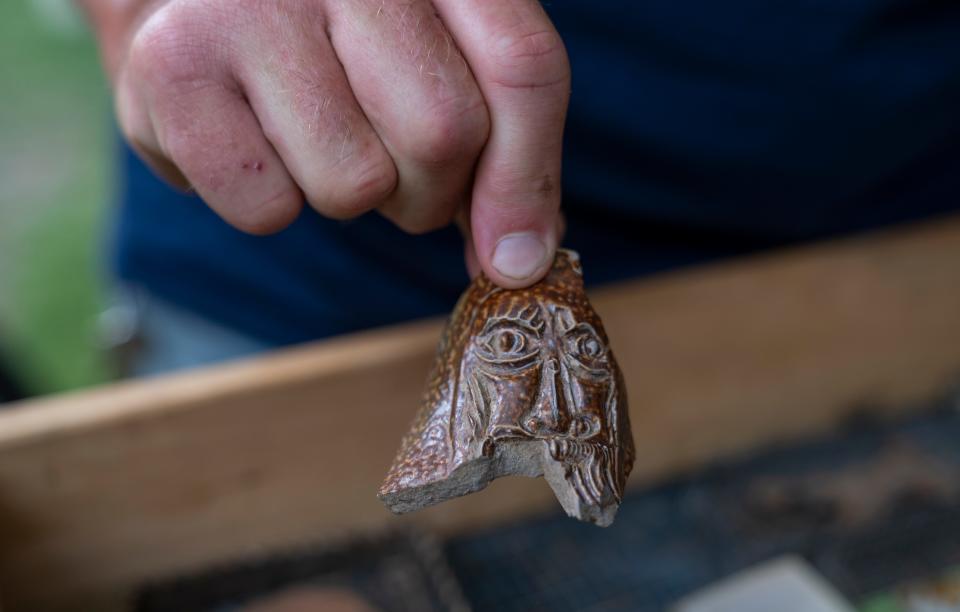 Lee McBee, staff archaeologist for the Jamestown Rediscovery Foundation, holds a fragment of a decorated pottery vessel found at the 