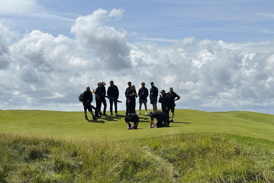 Green-keeprs and staff clear the remains of material thrown onto the 17th green area by Just Stop Oil protesters during the second day of the British Open Golf Championships at the Royal Liverpool Golf Club in Hoylake, England, Friday, July 21, 2023. (AP Photo)