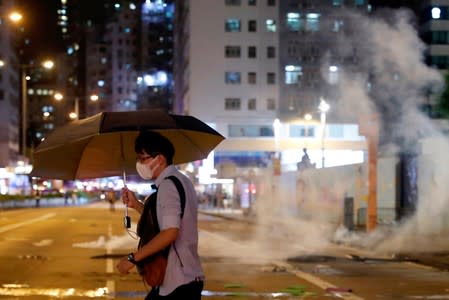 A man runs away from tear gas as riot police try to disperse anti-extradition bill protesters during a protest at Prince Edward in Hong Kong