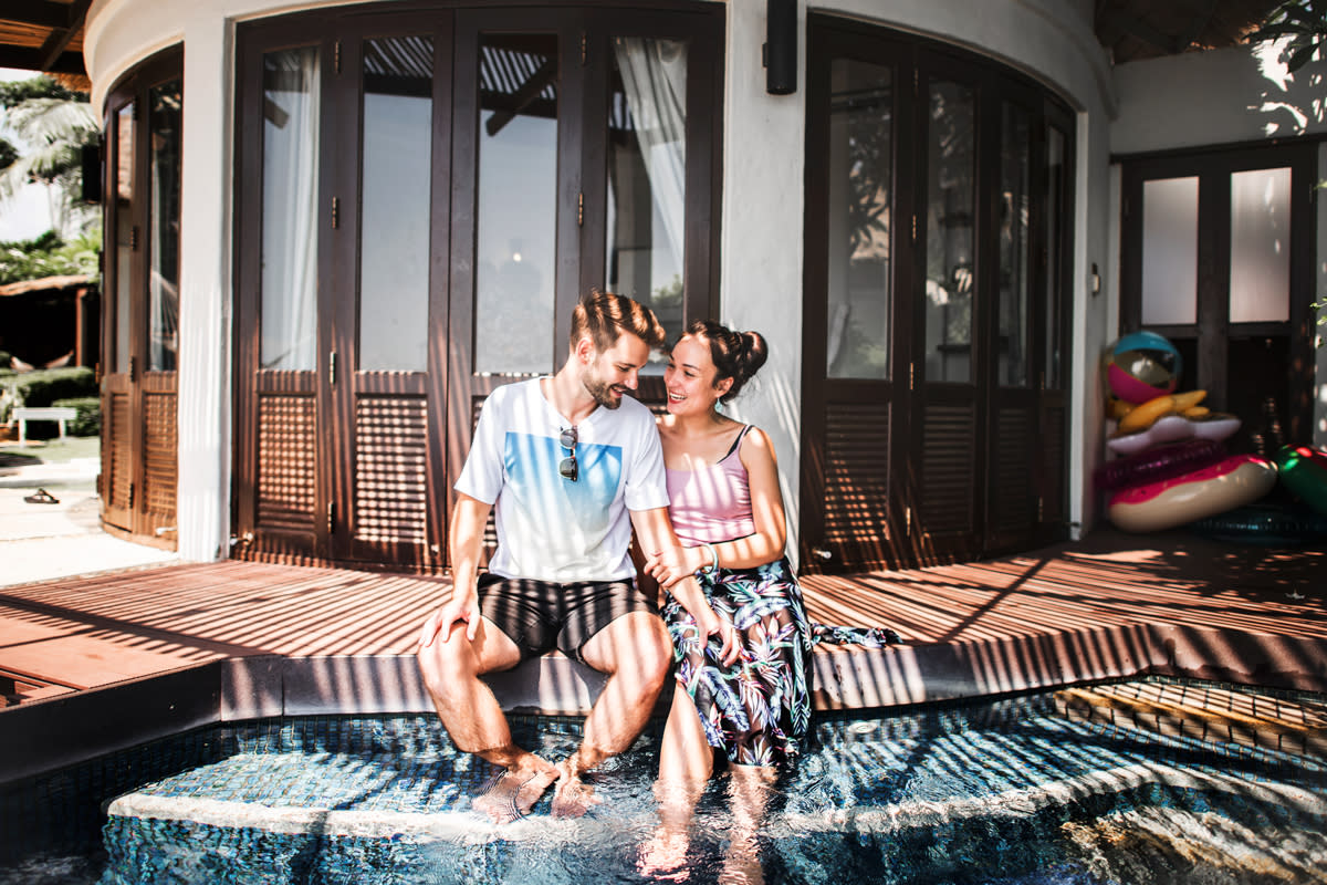 A couple relax by putting their feet in their pool. 