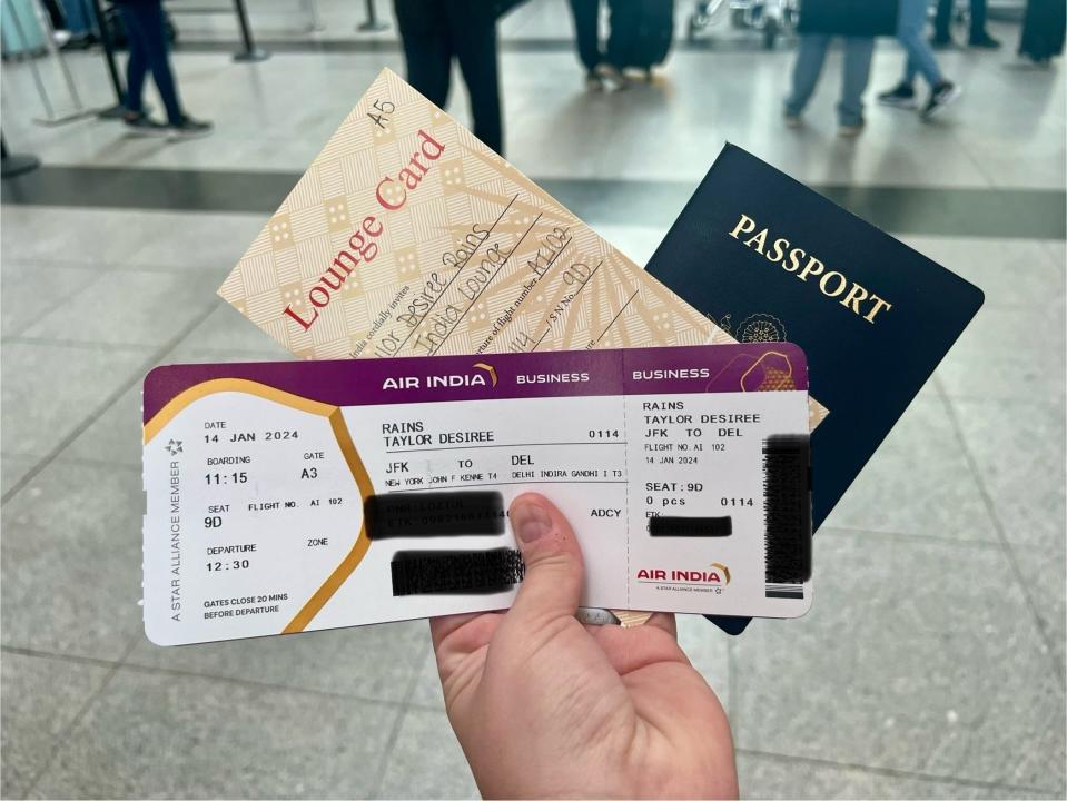 Author holding boarding pass, lounge ticket, and passport.