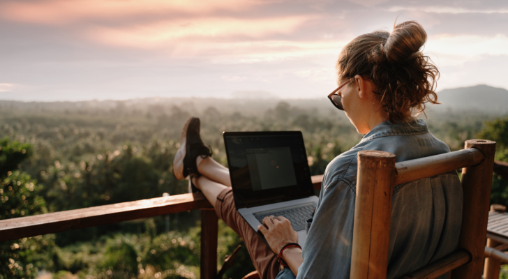 remote working. woman working on a laptop outside watching sunrise.