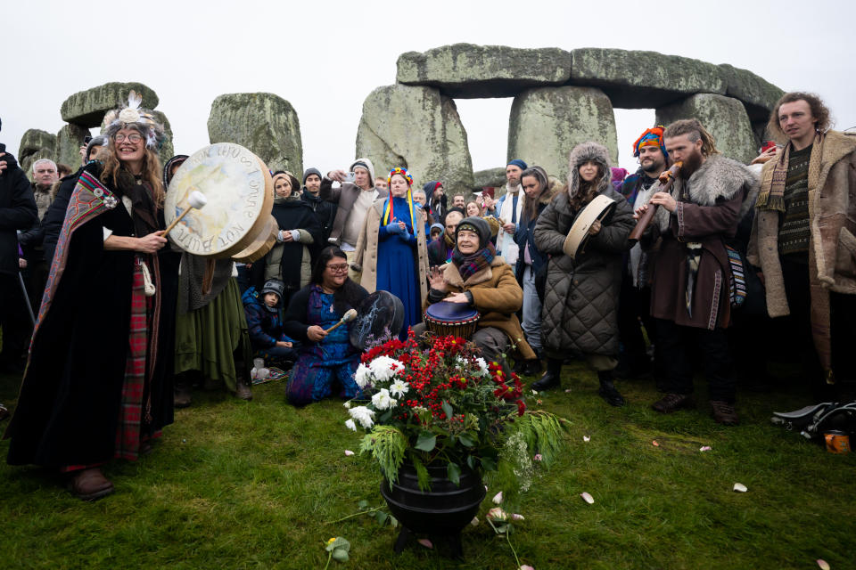 AMESBURY, ENGLAND - DECEMBER 22: People greet the sunrise at Stonehenge, on December 22, 2022, in Amesbury, United Kingdom. The famous historic stone circle, a UNESCO listed ancient monument and World Heritage Site, attracts visitors to celebrate the sunrise closest to the Winter Solstice, the shortest day of the year. The event is claimed to be more important in the pagan calendar than the summer solstice, because it marks the 're-birth' of the Sun for the New Year. (Photo by Finnbarr Webster/Getty Images)