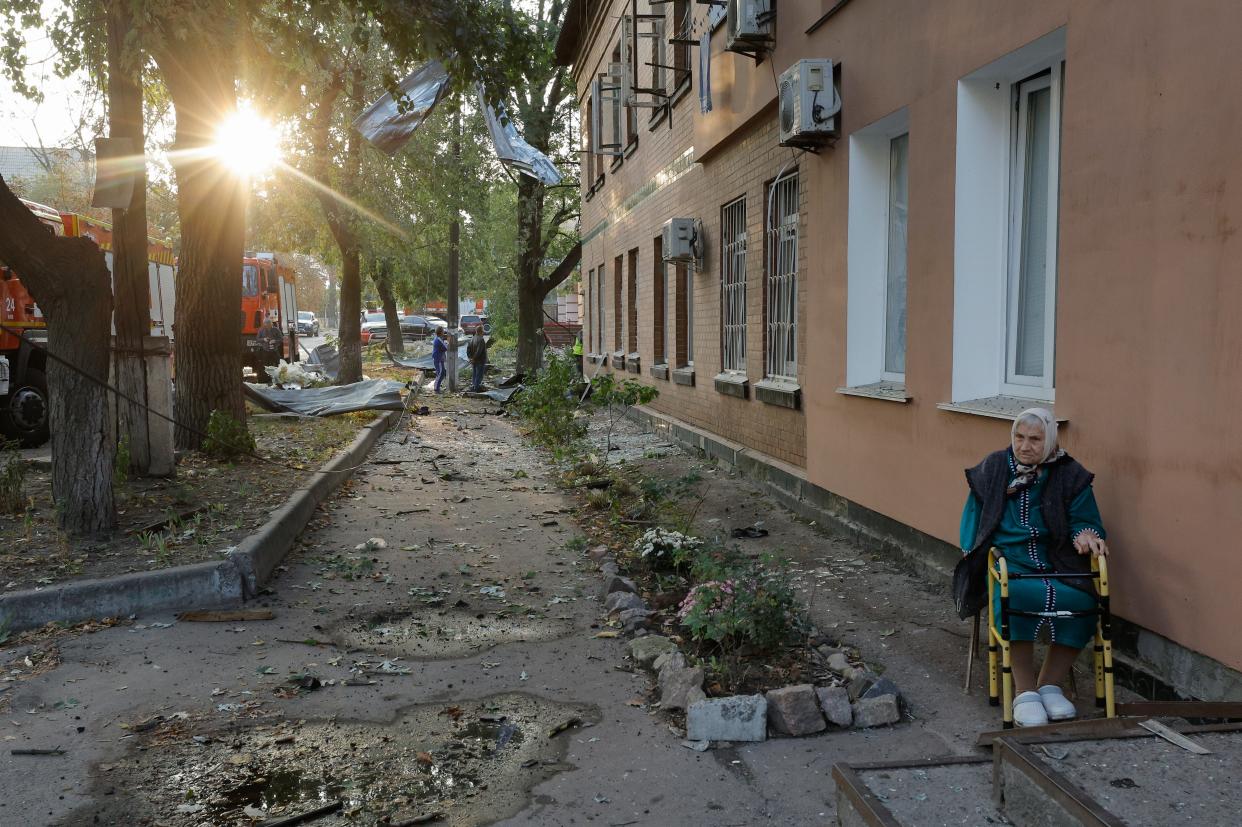 An elderly woman sits near her home in Kyiv where debris from a missile fell (EPA)