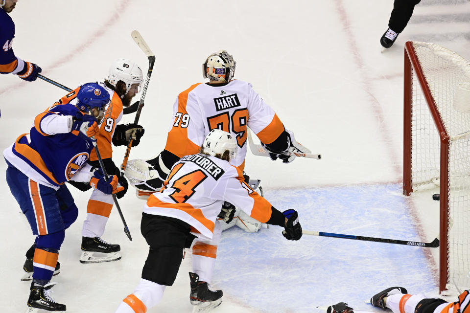 Philadelphia Flyers goaltender Carter Hart (79) looks back as the puck crosses the goal line on a shot by New York Islanders center Leo Komarov as Flyers center Sean Couturier (14) reaches into the net during second-period NHL Stanley Cup Eastern Conference playoff hockey game action in Toronto, Saturday, Aug. 29, 2020. (Frank Gunn/The Canadian Press via AP)