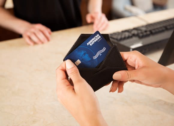 Female hands pulling an American Express card from a wallet.