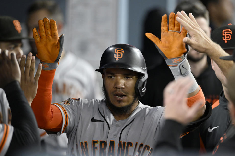 San Francisco Giants' Thairo Estrada is congratulated by teammates in the dugout after hitting a solo home run against the Los Angeles Dodgers during the sixth inning of a baseball game in Los Angeles, Friday, Sept. 22, 2023. (AP Photo/Alex Gallardo)