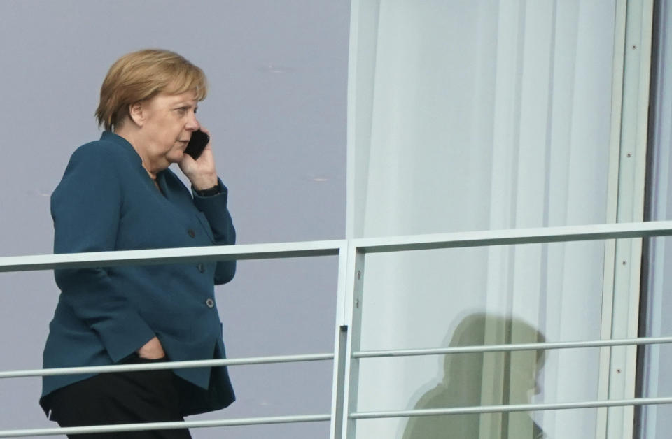 German Chancellor Angela Merkel makes a telephone call on a balcony of the Chacellery in Berlin, Germany, Friday, Sept. 20, 2019. The German government is scrambling to agree a package of measures for tackling global warming, as protesters prepare to stage rallies across the country demanding decisive action against climate change. (Kay Nietfeld/dpa via AP)