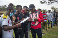 Young Ugandans check the voters listings as they wait to vote in Kampala, Uganda, Thursday, Jan. 14, 2021. Ugandans are voting in a presidential election tainted by widespread violence that some fear could escalate as security forces try to stop supporters of leading opposition challenger BobiWine from monitoring polling stations.(AP Photo/Jerome Delay)