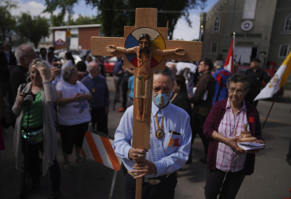 FILE - Elmer Waniandy raises the crucifix as he leads his fellow parishioner into the rededicated and newly renovated Sacred Heart Church of the First Peoples sanctuary, July 17, 2022, in Edmonton, Alberta. Pope Francis’ trip to Canada, which begins Sunday July 24, 2022, to apologize for the horrors of church-run Indigenous residential schools marks a radical rethink of the Catholic Church’s missionary legacy in the Americas, spurred on by the first American pope and the discovery of hundreds of unmarked graves at the school sites. (AP Photo/Jessie Wardarski, File)