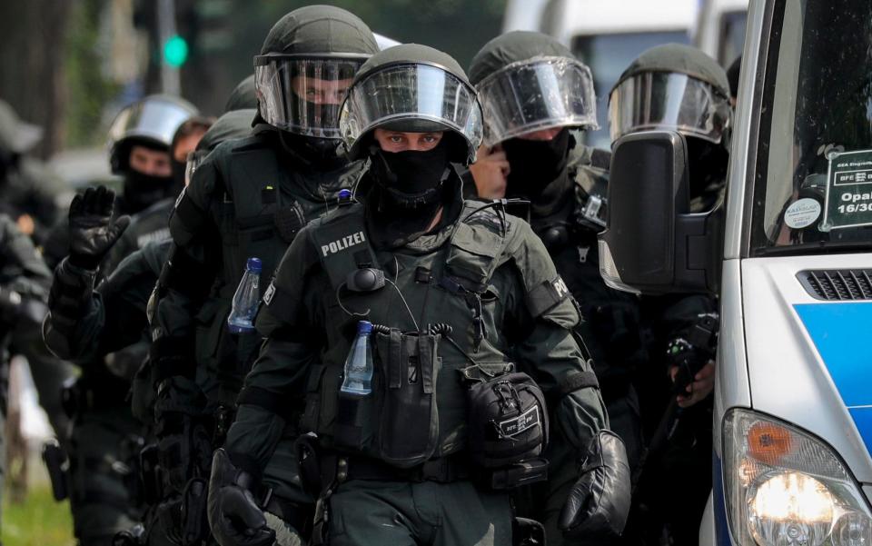 German riot police walk next to a police vehicle during a rally outside Schlump station  - Credit: EPA/ARMANDO BABANI