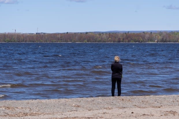 A person stands along the shore of the Ottawa River in Britannia Park on a sunny spring day on May 12.