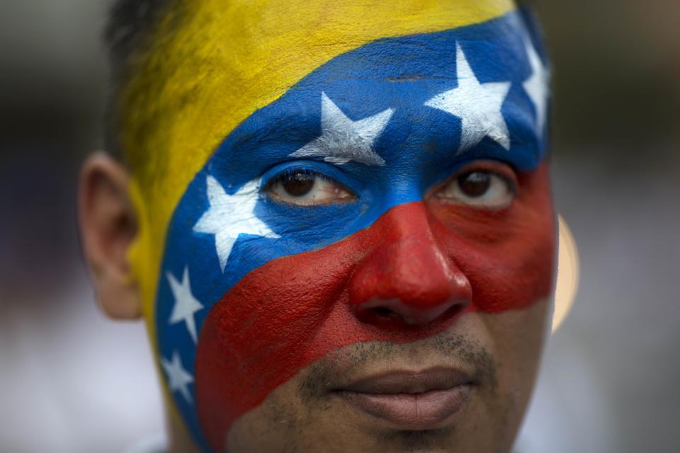 David Aranguren, his face painted with a representation of Venezuela's national flag, poses for a photo during an anti-government demonstration in Caracas, Venezuela, Saturday, Feb. 22, 2014. Supporters and opponents of the government of President Nicolas Maduro are holding competing rallies in the bitterly divided country. (AP Photo/Rodrigo Abd)