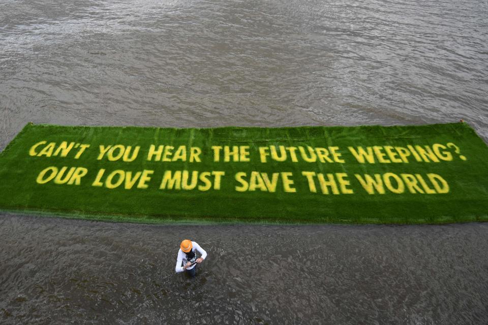 June 25, 2021: A giant banner declaring an environmental message, which is grown on a carpet of living grass and tells governments to act now in the lead-up to COP26, floats on the river Thames in central London having been placed on the water by Extinction Rebellion climate activists.