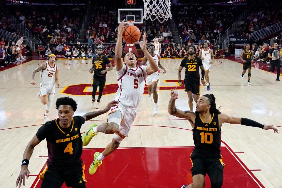 Southern California guard Boogie Ellis (5) drives to the basket between Arizona State guard Desmond Cambridge Jr. (4) and guard Frankie Collins (10) during the first half of an NCAA college basketball game on March 4, 2023, in Los Angeles.