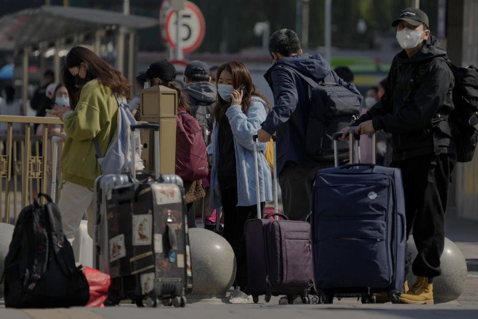 Travelers wearing face masks wait for their transports near a train station in Beijing, Thursday, Oct. 6, 2022. Sprawling Xinjiang is the latest Chinese region to be hit with sweeping COVID-19 travel restrictions, as China further ratchets up control measures ahead of a key Communist Party congress later this month. (AP Photo/Andy Wong)