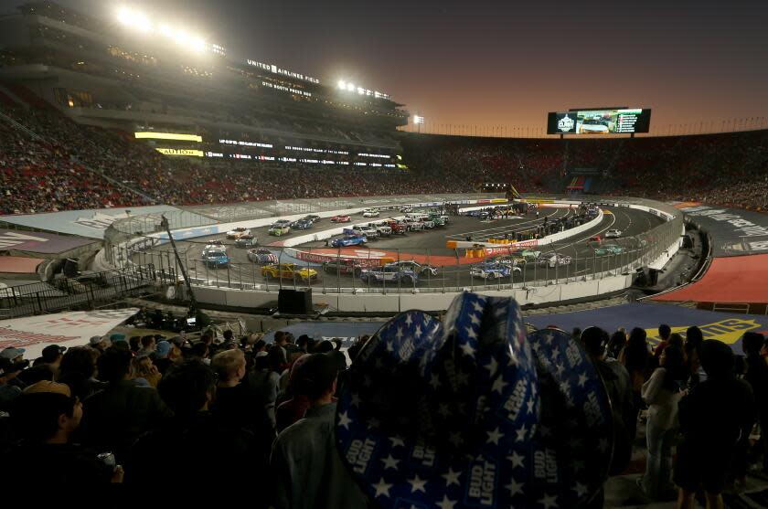 Cars race around a quarter-mile oval at sunset during NASCAR's season-opening Busch Light Clash at the Coliseum