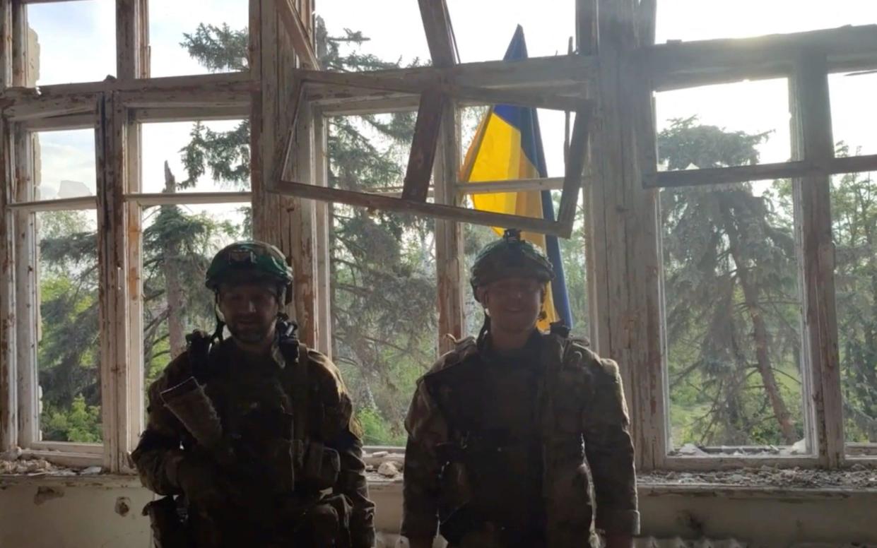 Ukrainian soldiers stand in front of a Ukrainian flag at a building, during an operation that claims to liberate the first village amid a counter-offensive, in a location given as Blahodatne, Donetsk Region, Ukraine, in this screengrab taken from a handout video released on June 11, 2023. 68th Separate Hunting Brigade 'Oleksy Dovbusha'/Handout via REUTERS THIS IMAGE HAS BEEN SUPPLIED BY A THIRD PARTY. NO RESALES. NO ARCHIVES. MANDATORY CREDIT. REUTERS WAS NOT ABLE TO INDEPENDENTLY VERIFY THE LOCATION OF THE VIDEO AND THE DATE IT WAS FILMED. - 68th Separate Hunting Brigade 'Oleksy Dovbusha'/Handout via REUTERS