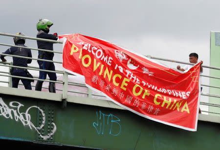 Traffic enforcers remove a banner reading "Welcome to the Philippines, Province of China" hanging on an overpass along the C5 road intersection in Taguig, Metro Manila, Philippines July 12, 2018. REUTERS/Erik De Castro