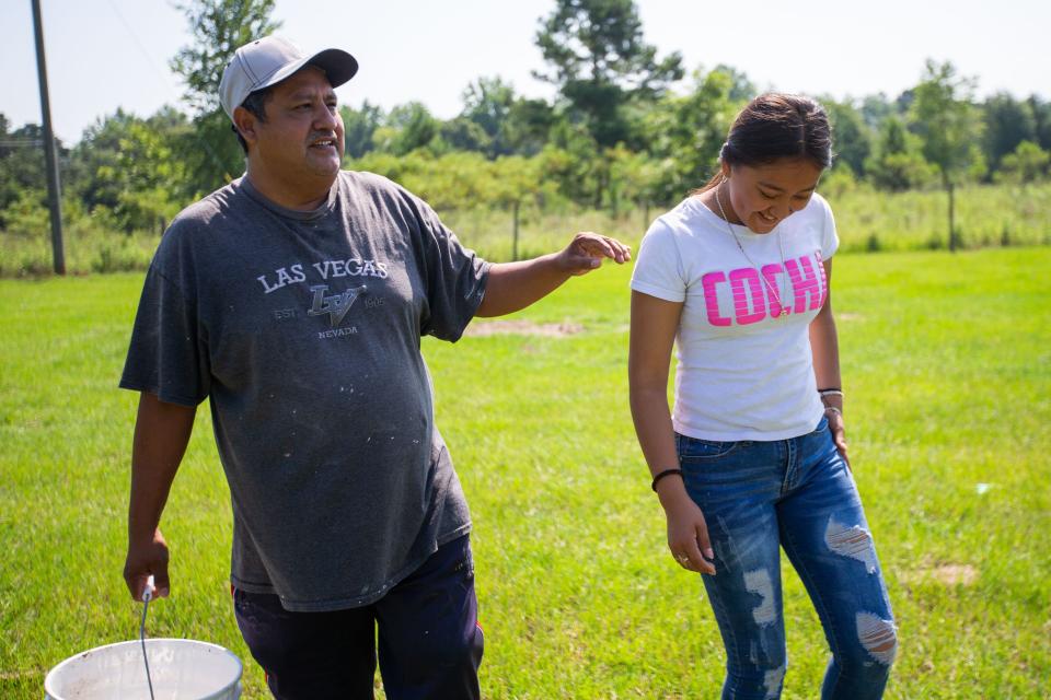 Rubi Sandoval, 15, right, walks with her father while feeding their livestock in Chattahoochee, Florida on Wednesday, June 28, 2023. 