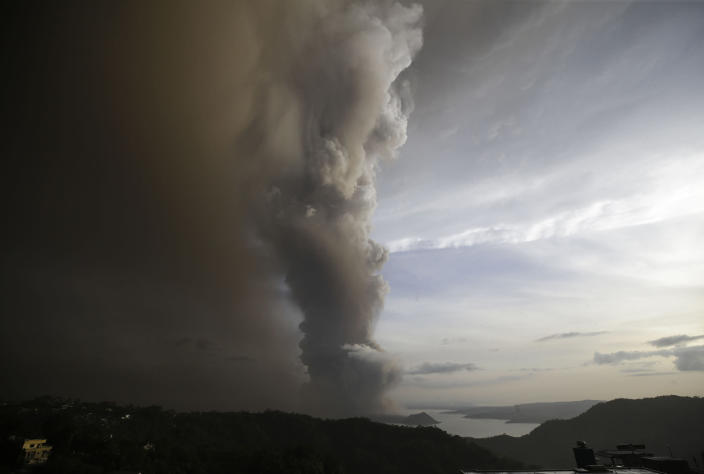 In this Sunday, Jan. 12, 2020, photo, Taal Volcano spews ash as it erupts, in Tagaytay, Cavite province, outside Manila, Philippines. A tiny volcano near the Philippine capital that draws many tourists for its picturesque setting in a lake belched steam, ash and rocks in a huge plume Sunday, prompting thousands of residents to flee and officials to temporarily suspend flights. (AP Photo/Aaron Favila)