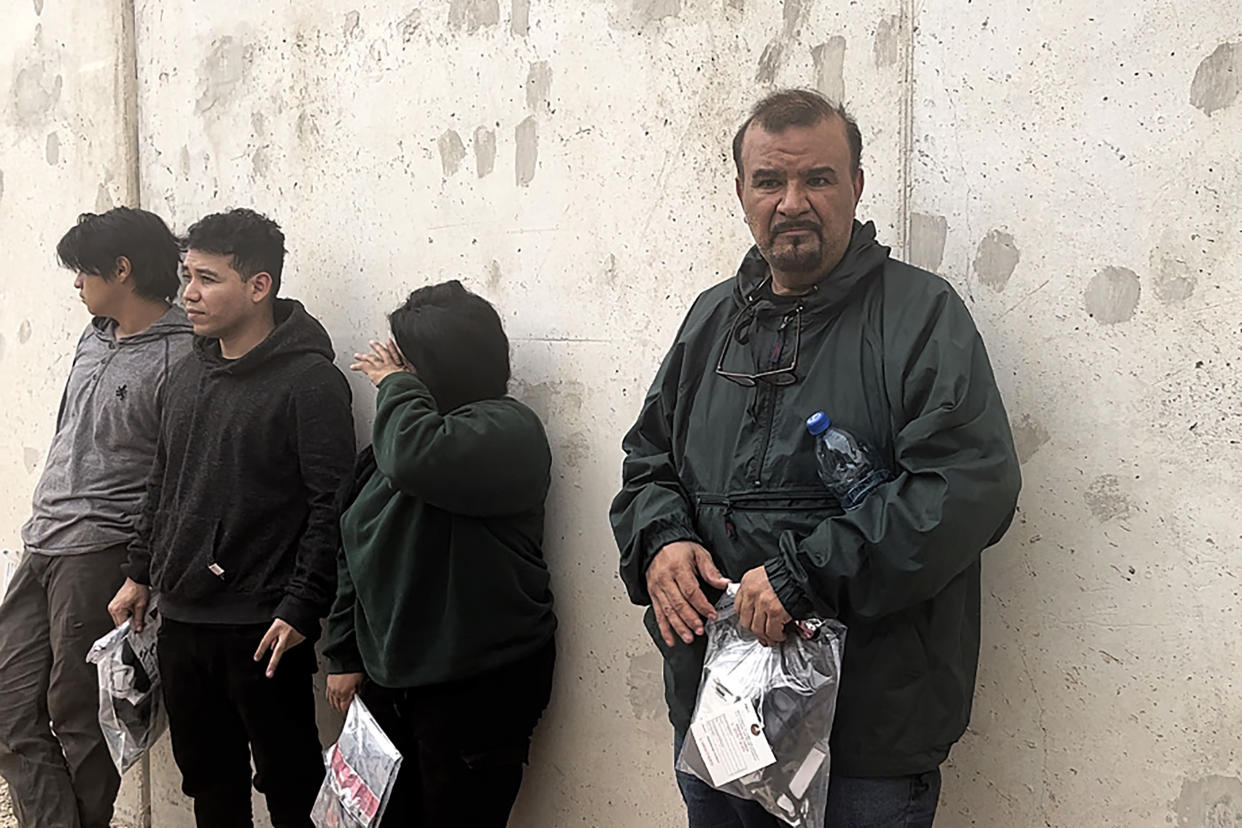 A man from Mexico along with a Mexican woman and two men from El Salvador stand by the border wall after being apprehended by Border Patrol on May 4, 2023.  (NBC News)