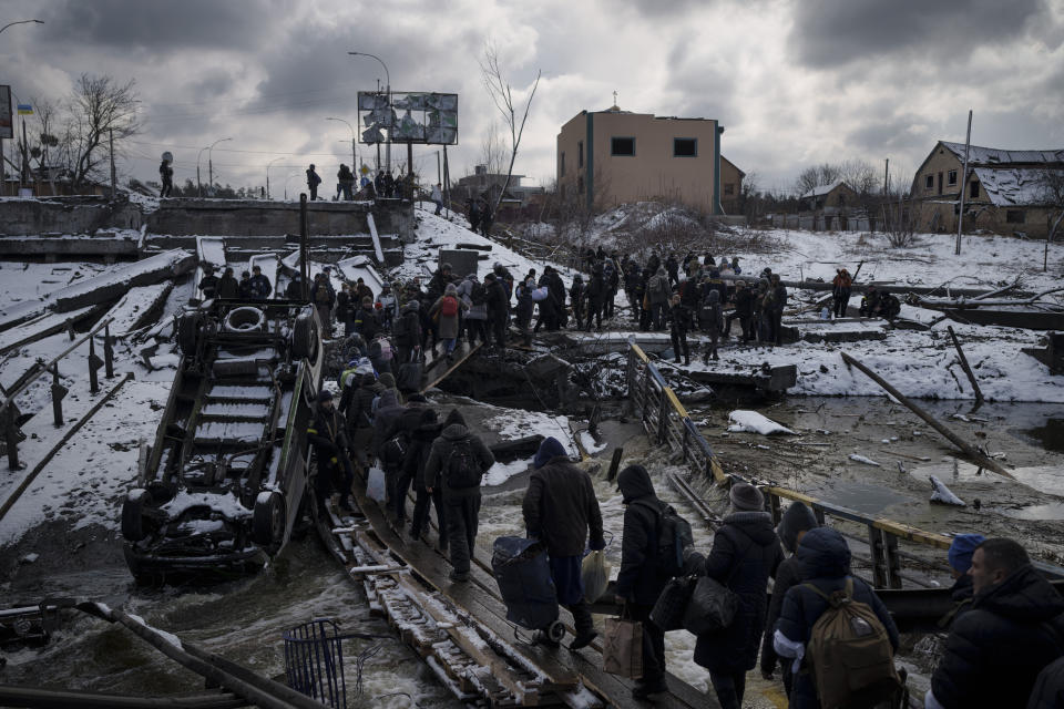 Ukrainians cross an improvised path under a destroyed bridge while fleeing Irpin, in the outskirts of Kyiv, Ukraine, Tuesday, March 8, 2022. Demands for ways to safely evacuate civilians have surged along with intensifying shelling by Russian forces, who have made significant advances in southern Ukraine but stalled in some other regions. Efforts to put in place cease-fires along humanitarian corridors have repeatedly failed amid Russian shelling. (AP Photo/Felipe Dana)