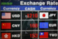 A man wearing a face mask is reflected on an electronic foreign currency exchange rates in downtown Seoul, South Korea, Tuesday, March 31, 2020. Asian shares surged Tuesday after a rally in U.S. stocks, mostly spurred by health care companies' announcements of developments that could aid in the coronavirus outbreak.(AP Photo/Lee Jin-man)