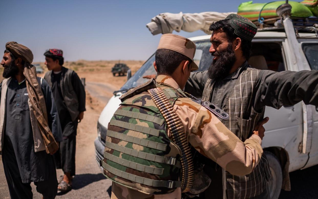 An Afghan police officer searches travelers at a checkpoint on the eastern outskirts of Lashkar Gah city, Helmand, Afghanistan on May 25, 2019. - JIM HUYLEBROEK
