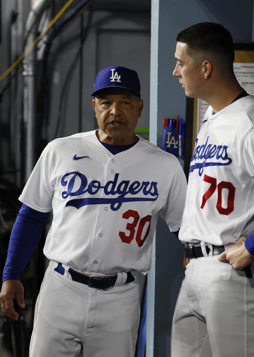 Dodgers manager Dave Roberts speaks with pitcher Bobby Miller in the dugout.