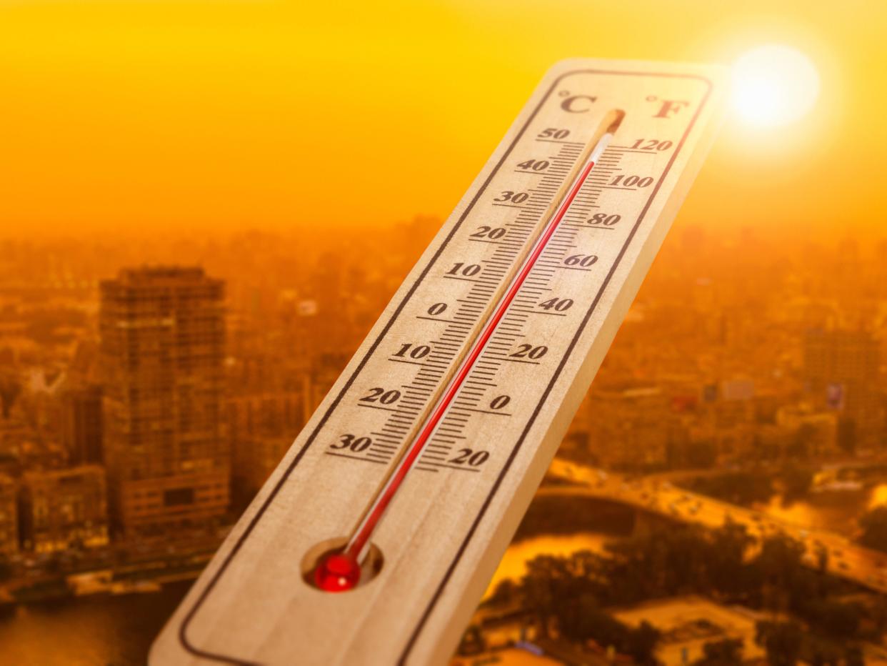 A thermometer showing a hot day in a city.