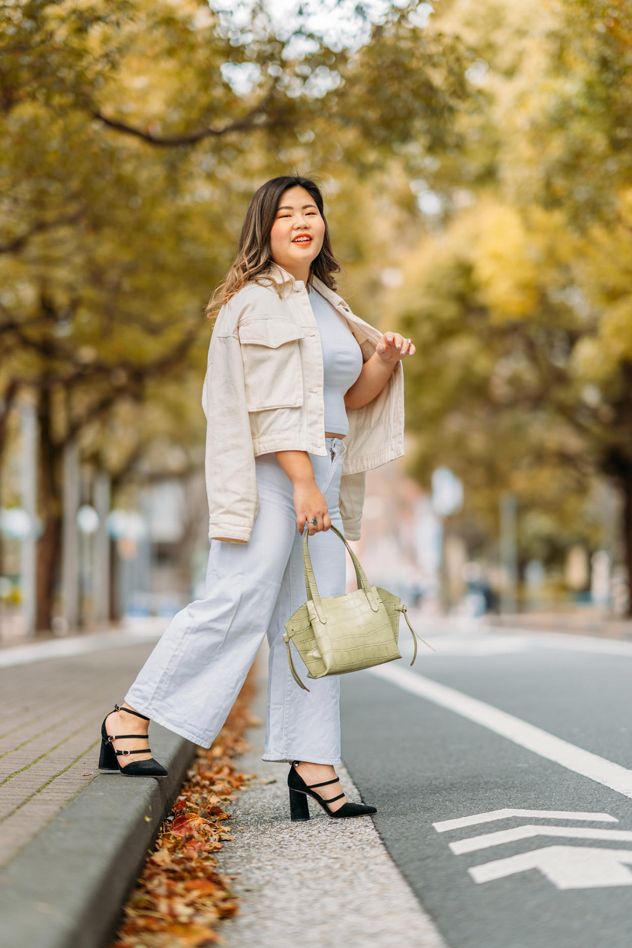 A full size portrait of a young woman in the street in autumn.