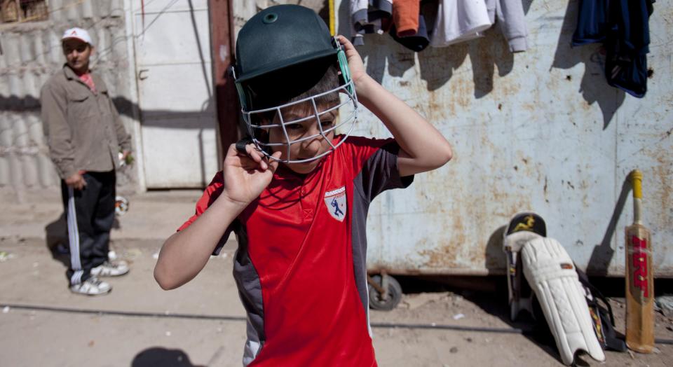 Caacupe cricket team Maxi Rubin puts on his helmet during a training session at the Villa 21-24 slum in Buenos Aires, Argentina, Saturday, March 22, 2014. The International Cricket Council has recognized the team, formed from the children of the Villa 21-24 shantytown, honoring them as a global example for expanding the sport, which in certain countries, like India, is widely played, but in many parts of the world restricted to elite sectors of society. Introducing cricket in the slum began in 2009 as an idea to transform the game into a social integration mechanism, before that it rarely breached the gates of the country's upscale private schools. (AP Photo/Natacha Pisarenko)