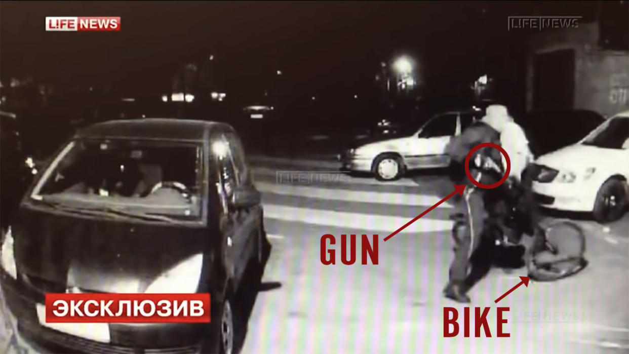A blurry image marked Life News of Vadim Krasikov on a bicycle, with a red circle pointing to a gun in his hand and an arrow pointing to his bike, as well as a label in Russian saying Exclusive.