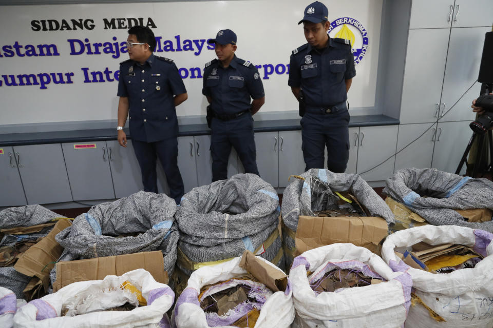 FILE - In this Monday, May 8, 2017 file photo, Malaysian Customs officials stand next to seized pangolin scales during a news conference in Sepang, Malaysia, announcing the 9.2 million ringgit ($2.1 million) seizure, believed to have been smuggled from Africa. The price of pangolin scales in China has risen from $11 per kilogram (2.2 pounds) in the 1990s to $470 in 2014, according to researchers at Beijing Forestry University. (AP Photo/Vincent Thian)