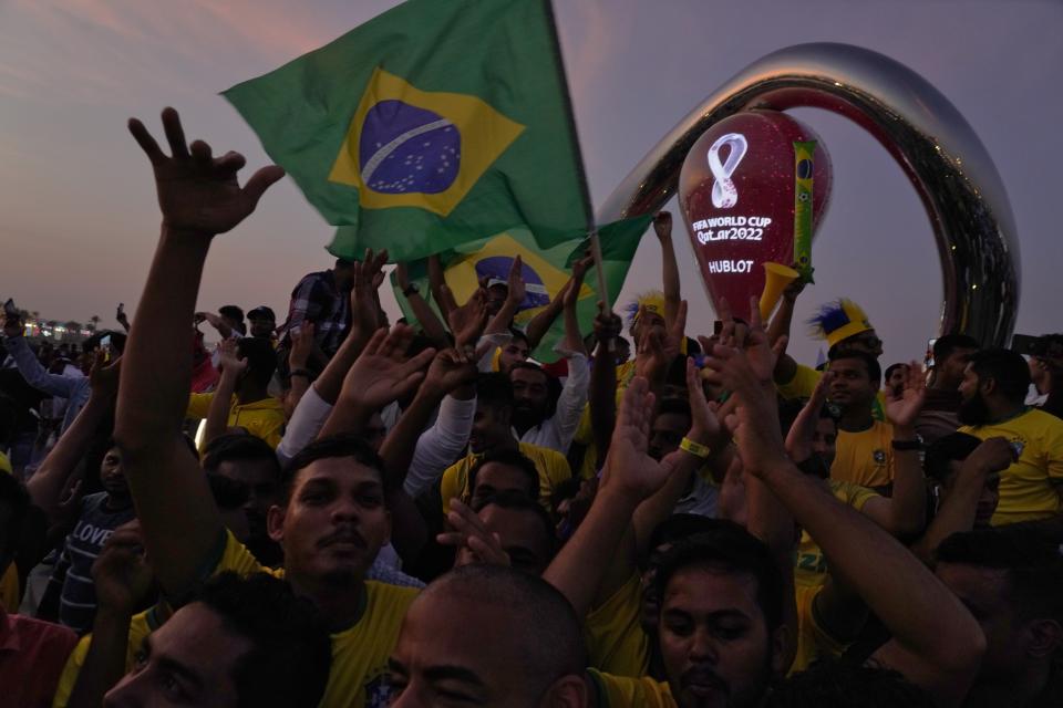 Fans cheer and wave Brazilian flags in front of the World Cup countdown clock in Doha, Qatar, Friday, Nov. 18, 2022. Fans poured into Qatar on Friday ahead of the Middle East's first World Cup as Doha ordered beers not to be poured out at stadiums during the tournament — a last-minute surprise largely welcomed by the country's conservative Muslims and shrugged off by giddy fans. (AP Photo/Jon Gambrell)