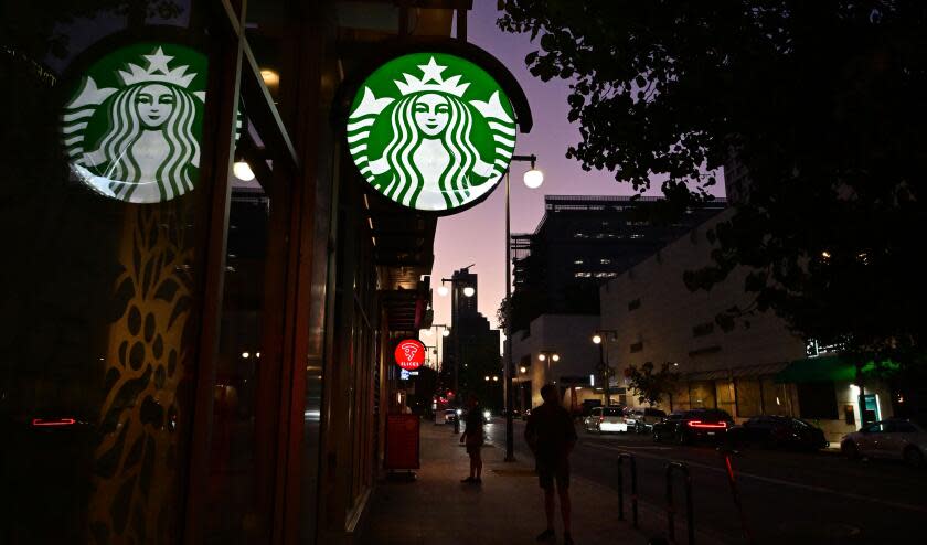 People stand outside a Starbucks closed for the day in Los Angeles, California on July 12, 2022. - Starbucks will close six locations in Los Angeles, including this one in downtown, by the end of the month. Company officials cite safety concerns for workers and customers as issues facing the nation, from racism to lack of access to health care to a growing mental health crisis, impact the coffee chain. (Photo by Frederic J. BROWN / AFP) (Photo by FREDERIC J. BROWN/AFP via Getty Images)